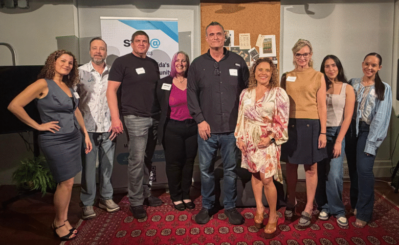SFIMA board members posing together in front of an SFIMA banner.